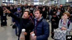 Los pasajeros miran hacia arriba a un tablero del horario del tren mientras que esperan en la estación de Penn de Nueva York, lunes, 3 de abril, 2017.