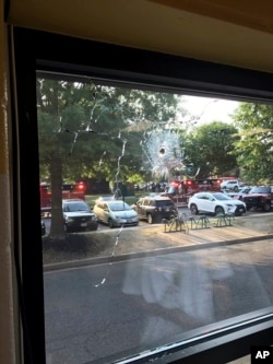 Emergency personnel are seen through a window with a bullet hole in Alexandria, Virginia, June 14, 2017.