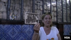 Thylda Lellouche holds a photo of her Tunisian grandfather and uncle while visiting the Ghriba synagogue in Djerba, Tunisia. (L. Bryant/VOA)