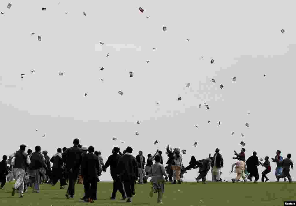 Supporters of Afghan presidential candidate Ashraf Ghani Ahmadzai try to catch leaflets during an election campaign in Kunduz province, northern Afghanistan.