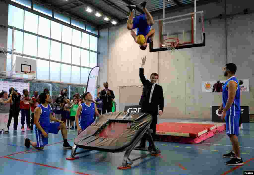 French President Emmanuel Macron (C) reacts as he takes part in display of basketball skills during a visit at the Jesse Owens gymnasium in Villetaneuse, north of Paris, France, February 27, 2018.