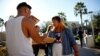 Kathryn Quintin of the policy and education group Young Invincibles, right, offers free pizza to students waiting in line to vote at the ASU Palo Verde West polling station during the U.S. midterm elections in Tempe, Ariz.. Nov. 6, 2018. 