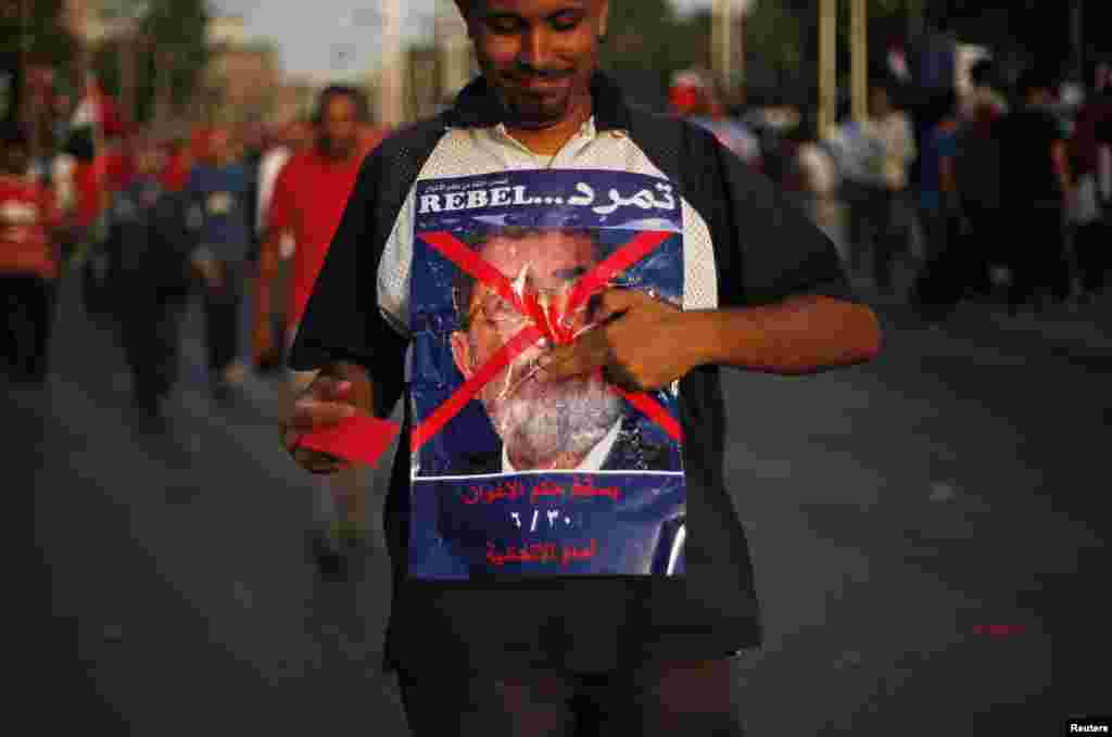 A protester opposing Egyptian President Mohamed Morsi holds a poster during a protest in front of the presidential palace in Cairo, June 30, 2013.