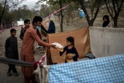 Displaced Afghans distribute food donations at an internally displaced persons camp in Kabul, Afghanistan, Sept. 13, 2021.