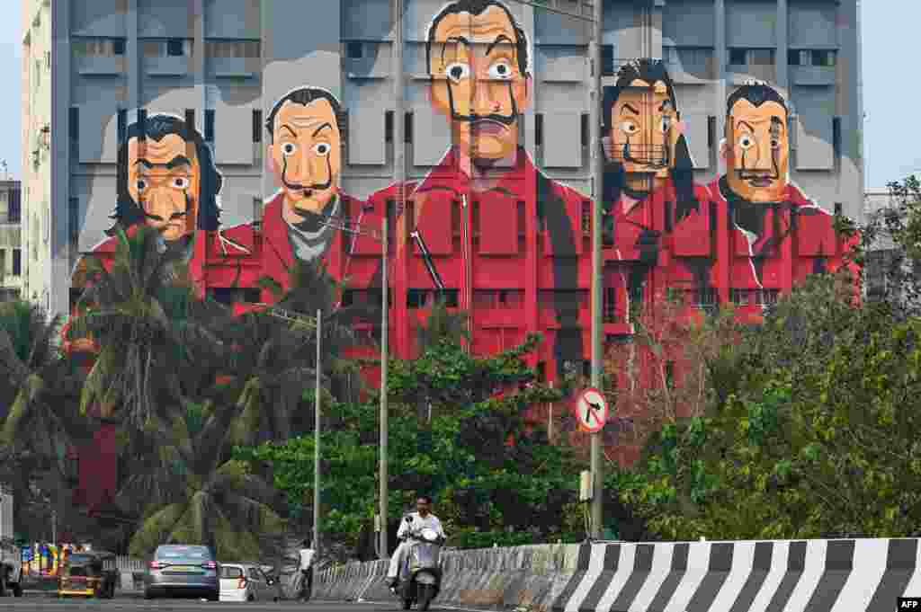 Commuters drive past a painting of characters from the Spanish TV show 'Money Heist' in Mumbai, India.