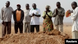 FILE - People gather around a grave, where three murdered family members were buried together, in Jos, in Nigeria's Plateau state, December 28, 2011, following clashes between farmers and herders.