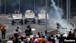 Para demonstran oposisi melemparkan batu-batu ke arah kendaraan militer di dekat pangkalan udara "La Carlota", Caracas, Venezuela, Selasa (30/4).