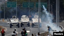 Des manifestants de l'opposition font face à des véhicules militaires près de la base aérienne Generalisimo Francisco de Miranda "La Carlota" à Caracas (Venezuela) le 30 avril 2019. REUTERS / Carlos Garcia Rawlins