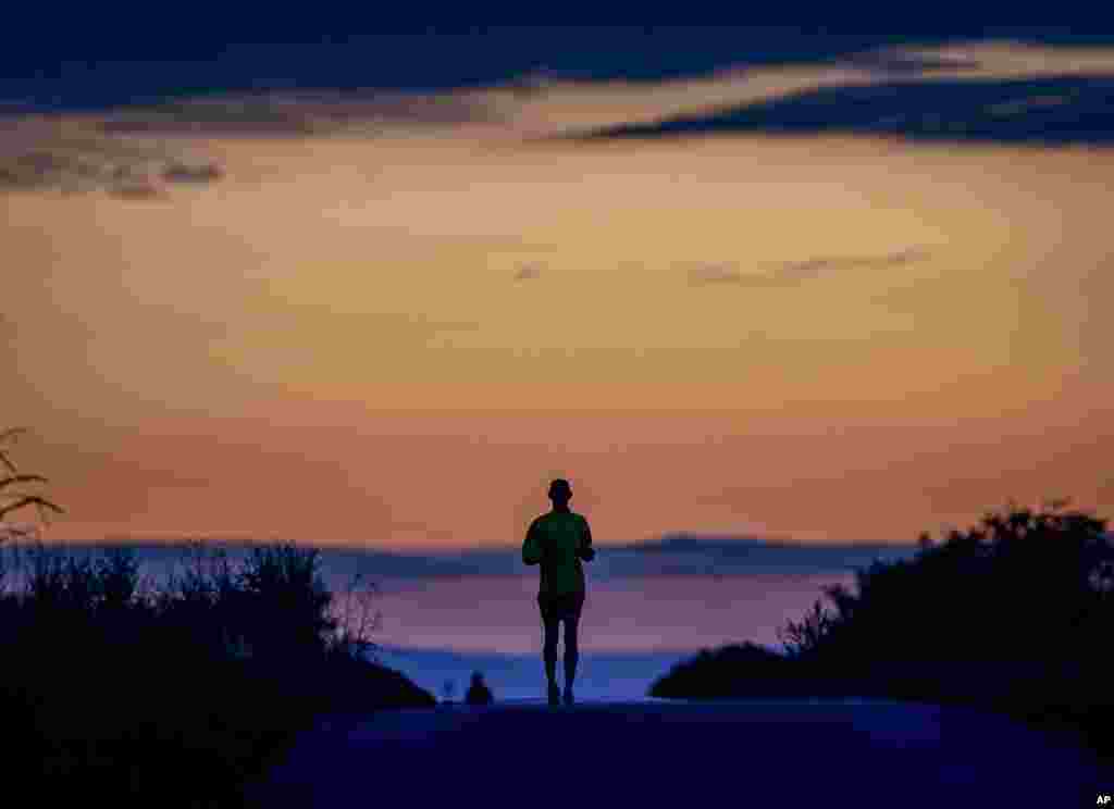 A man runs on a small road in the outskirts of Frankfurt, Germany, before sunrise.