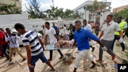 Somali men carry away the body of a civilian who was killed in a militant attack on a restaurant in Mogadishu, Somalia Thursday, June 15, 2017. 