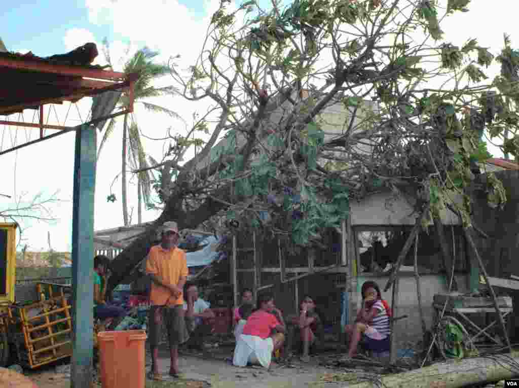 A family in front of their damaged home, Cebu, Philippines, Nov. 15, 2013. (Steve Herman/VOA)