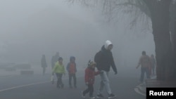 Orang-orang berjalan di hari yang berkabut di distrik Yanqing, Beijing, 27 Februari 2018.
