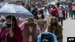 People queue for a free molecular testing and to be vaccinated at a makeshift health center on a street in downtown Lima on January 5, 2022.