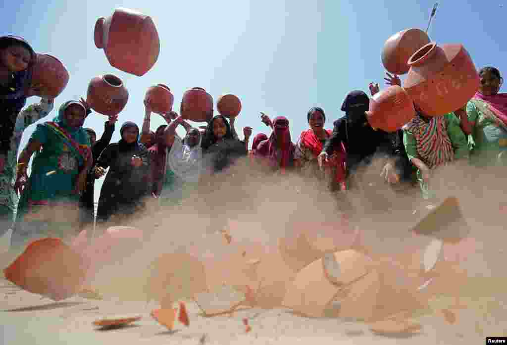 Para wanita melemparkan tempayan tanah liat ke tanah sebagai bentuk protes atas langkanya air bersih diluar kantor PDAM Ahmedabad, India.