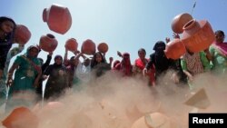 Women throw earthen pitchers onto the ground in protest against the shortage of drinking water outside the municipal corporation office in Ahmedabad, India, May 16, 2019.
