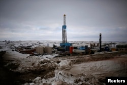FILE - An oil derrick is seen at a fracking site for extracting oil outside of Williston, North Dakota, on March 11, 2013.