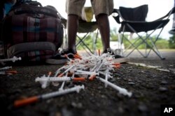 FILE - A drug user turns in his used syringes to volunteers from the Intercambios Puerto Rico needle exchange program, in order to get new, clean ones, in an area popular with drug users in Humacao, Puerto Rico, Dec. 14, 2018.