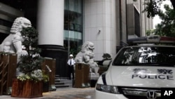 FILE - A security guard and police vehicle are seen outside the Guangzhou Intermediate People’s Court in China's southern Guangdong province, May 7, 2015.