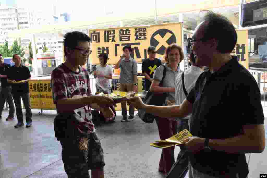 香港泛民立法會飯盒會召集人梁家傑（右）在街站向市民派發反對政改「袋住先」傳單 (美國之音湯惠芸拍攝)
