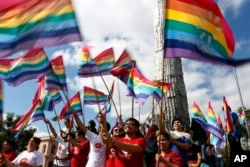 Gays and lesbians wave gay pride flags before a Kiss-A-Thon against homophobia in Asuncion, Paraguay, May 17, 2016.