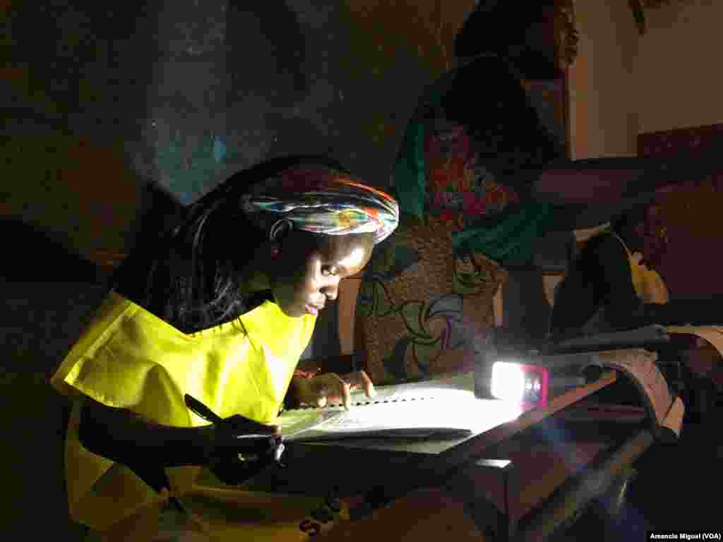 Funcionária de mesa de votos confere os dados usando uma lanterna. Wimby, Cabo Delgado, Moçambique 15 de Outubro 2019