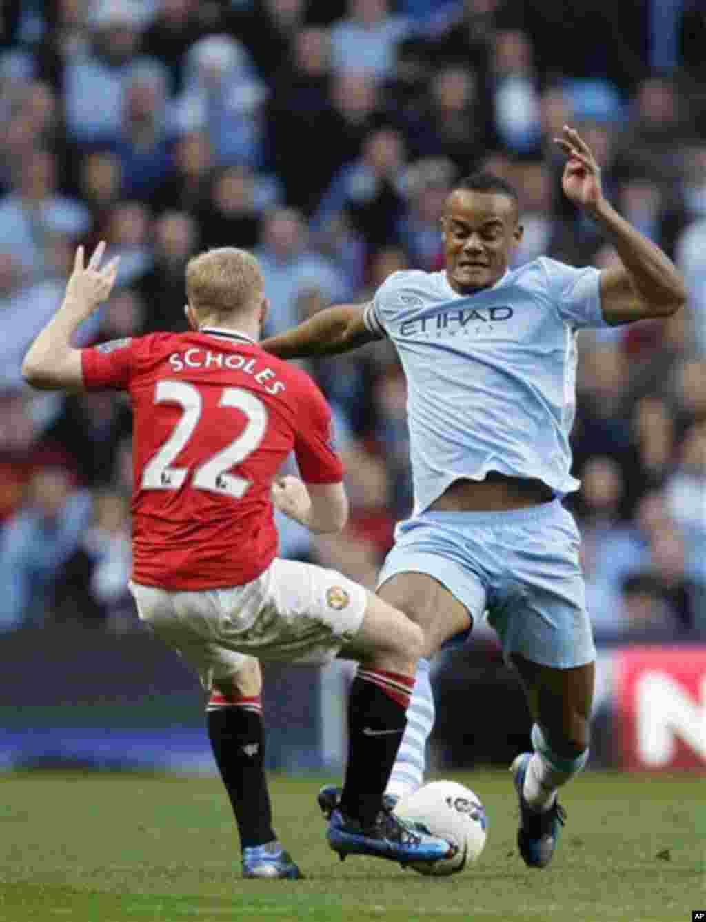 Manchester City's Vincent Kompany, right, fights for the ball against Manchester United's Paul Scholes during their English Premier League soccer match at The Etihad Stadium, Manchester, England, Monday, April 30, 2012. (AP Photo/Jon Super)