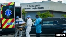 Emergency Medical Technicians (EMT) arrive with a patient while a funeral car begins to depart at North Shore Medical Center where the coronavirus disease (COVID-19) patients are treated, in Miami, Florida, U.S. July 14, 2020. REUTERS/Maria Alejandra Card