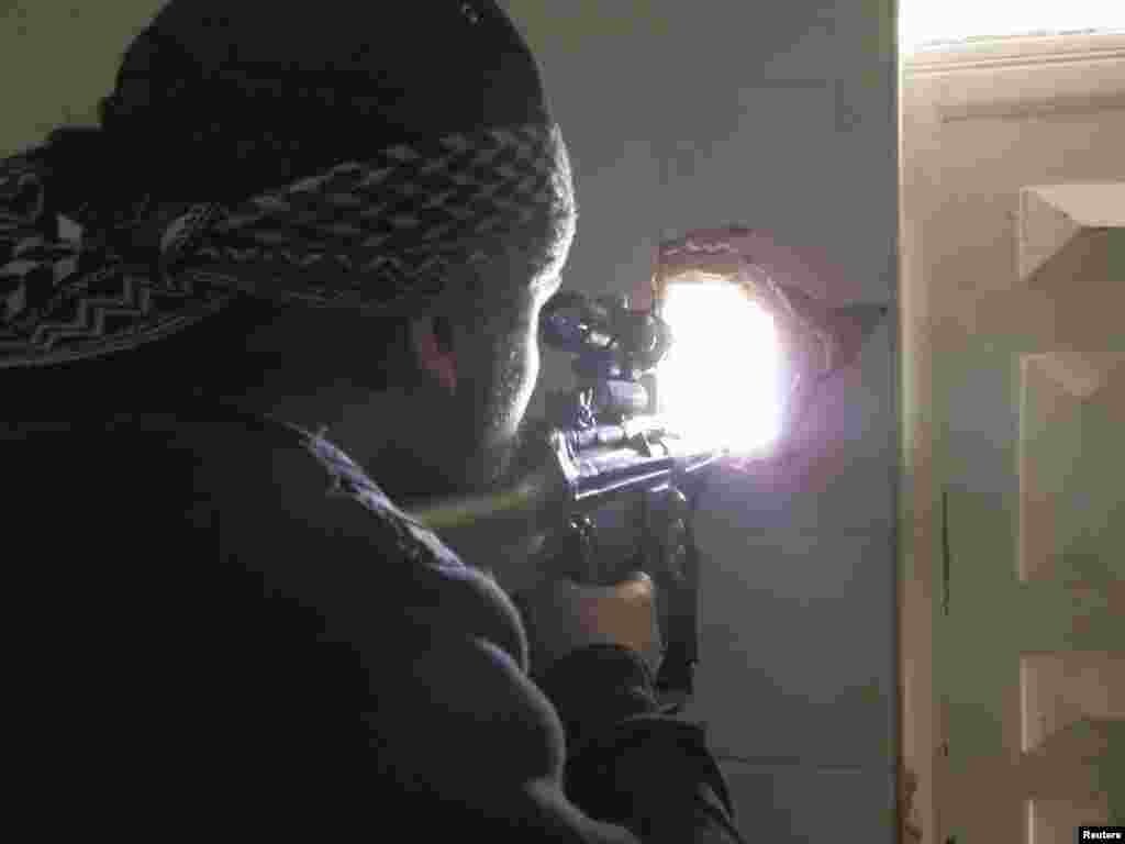 A member of the Free Syrian Army points his weapon through a hole in a wall as he takes up a defense position in Daraya February 4, 2013. (Shaam News Network) 