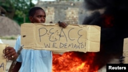A resident holds a sign as he participates in a protest against the recent attack by gunmen in the coastal Kenyan town of Mpeketoni, June 17, 2014. 