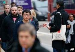 FILE - A pro-Brexit campaigner hands out leaflets at Liverpool Street station in London, March 23, 2016.