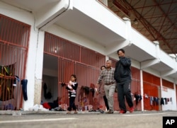 Migrants, mostly Syrians, walk in a stadium used for traditional Kirkpinar Oil Wrestling, waiting to cross to Europe near Turkey’s western border with Greece and Bulgaria, in Edirne, Turkey, Tuesday, Sept. 22, 2015.