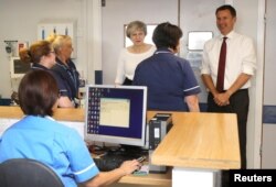FILE - Britain's PM Theresa May and Secretary of State for Health Jeremy Hunt speak to nurses and members of staff as they visit the Renal Transplant Unit at the Royal Liverpool University Hospital, Liverpool, Oct. 12, 2017.