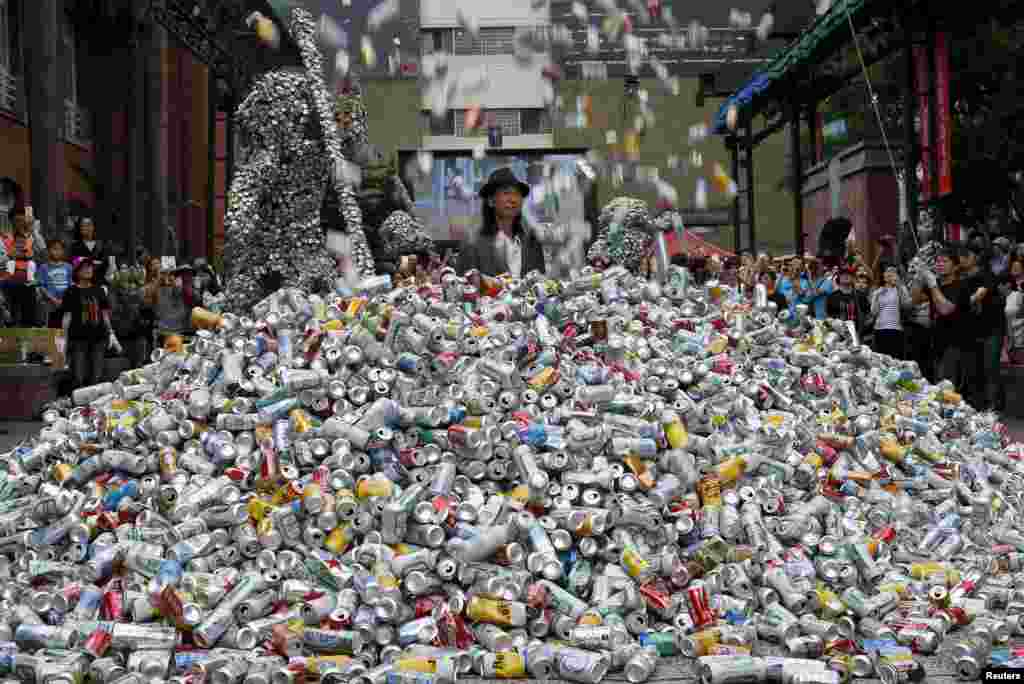 Artist Chin Chih Yang performs &quot;Kill Me or Change&quot; with 30,000 cans falling and burying the artist underneath a mountain of garbage, at the Museum of Contemporary Art in Taipei, Taiwan, April 23, 2016.