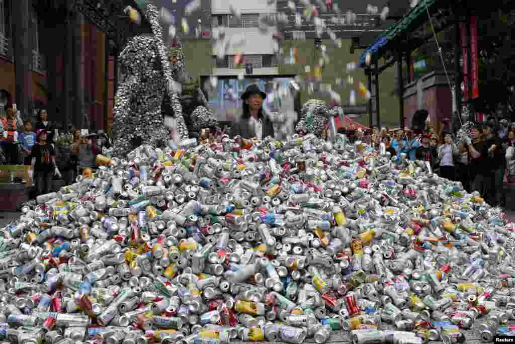 Seniman Chin Chih Yang memerankan aksi teatrikal &quot;Bunuh Saya atau Berubah&quot; menggambarkan dirinya terkubur dalam &quot;gunung sampah&quot; ribuan kaleng, pada pertunjukan di Museum Seni di Taipei, Taiwan.