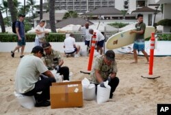 Hotel employees fill sandbags along the beach in preparation for Hurricane Lane in Honolulu, Aug. 23, 2018.