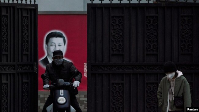 戴著口罩的行人從上海街頭一個有著習近平畫像的大門前經過。（2020年2月10日）