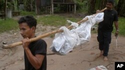 Workers carry a dead body in Songkhla province, southern Thailand, May 1, 2015. Police in Thailand found dozens of shallow graves in an isolated mountain area believed to have been used a trafficking camp.