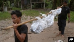 Workers carry a dead body in Songkhla province, southern Thailand, May 1, 2015. Police in Thailand found dozens of shallow graves in an isolated mountain area believed to have been used as a trafficking camp.