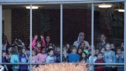 Estudiantes observan desde una ventana a la candidata demócrata a la nominación presidencial de su partido, senadora Elizabeth Warren, cuando llega para votar en las primarias del Supermartes en Cambridge, Massachusetts. Marzo 3 de 2020.