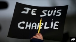 A Lebanese journalist holds up her pen and a French placard that reads, "I am Charlie." The killings in Paris at the satiric newspaper Charlie Hebdo has re-ignited debate about blasphemy. (AP Photo/Hussein Malla)