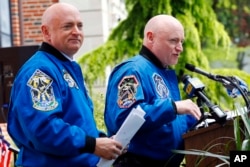 FILE - Retired astronaut Scott Kelly, right, speaks while standing next to his astronaut twin brother, Mark Kelly, during an event renaming the elementary school they attended, May 19, 2016, in West Orange, N.J.