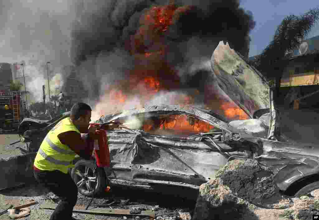 A Lebanese firefighter extinguishes a burned car at the site of an explosion, near the Kuwaiti Embassy and Iran&#39;s cultural center, in the suburb of Beir Hassan, Beirut, Lebanon, Feb. 19, 2014.