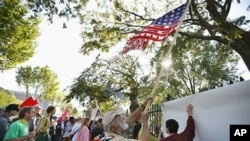 As part of Occupy DC activities, protesters wave a 'corporate America' flag at the fence in front of the White House in Washington, October 7, 2011.