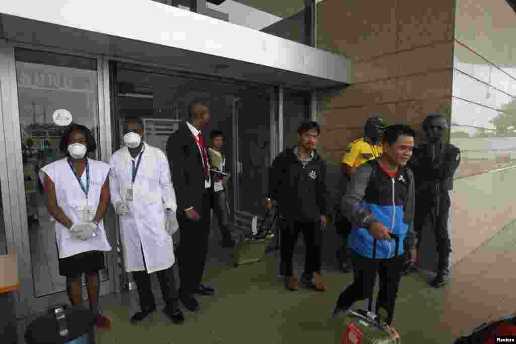 Ivory Coast banned air travellers from Guinea, Liberia and Sierra Leone on August 11. In this photo, people walk past health workers wearing protective masks and gloves at the Felix Houphouet Boigny international airport in Abidjan, Ivory Coast, Aug. 12, 2014.