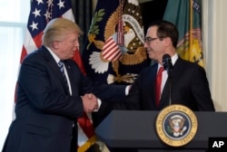 President Donald Trump shakes hands with Treasury Secretary Steven Mnuchin at the Treasury Department in Washington, April 21, 2017, where the president signed an executive order to review tax regulations set last year by his predecessor, as well as two memos to potentially reconsider major elements of the 2010 Dodd-Frank financial reforms passed in the wake of the Great Recession.