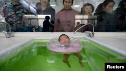 FILE - China has announced changes to existing laws that restricted families to one child, such as this one, going through swimming exercise at a maternal and child health care hospital in Taiyuan, Shanxi province, December 2012.