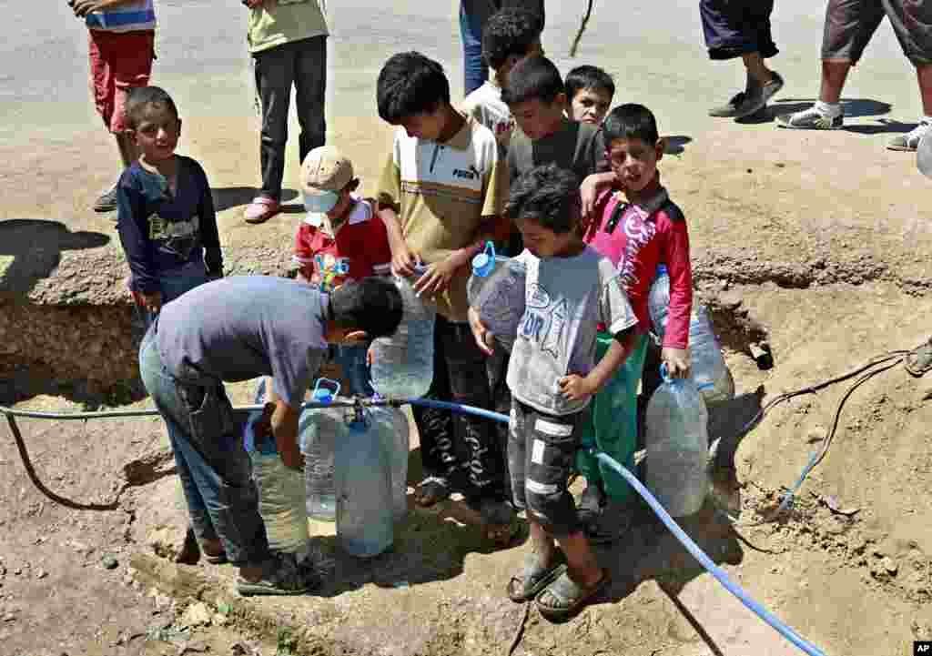 지난달 28일 레바논 내 시리아 난민캠프에서 난민들이 물통에 식수를 채우고 있다.