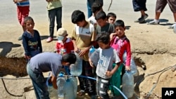 FILE - Syrian refugees fill up water bottles at a temporary refugee camp in the eastern Lebanese town of Faour near the border with Syria, August 28, 2013.