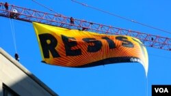 Greenpeace protesters unfurl a banner on a construction crane reading "RESIST," just blocks from the White House in downtown Washington, D.C., Jan.25, 2017 (B. Allen/VOA)