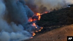 A wildfire burns along the hillside on May 14, 2014, in San Marcos, California.